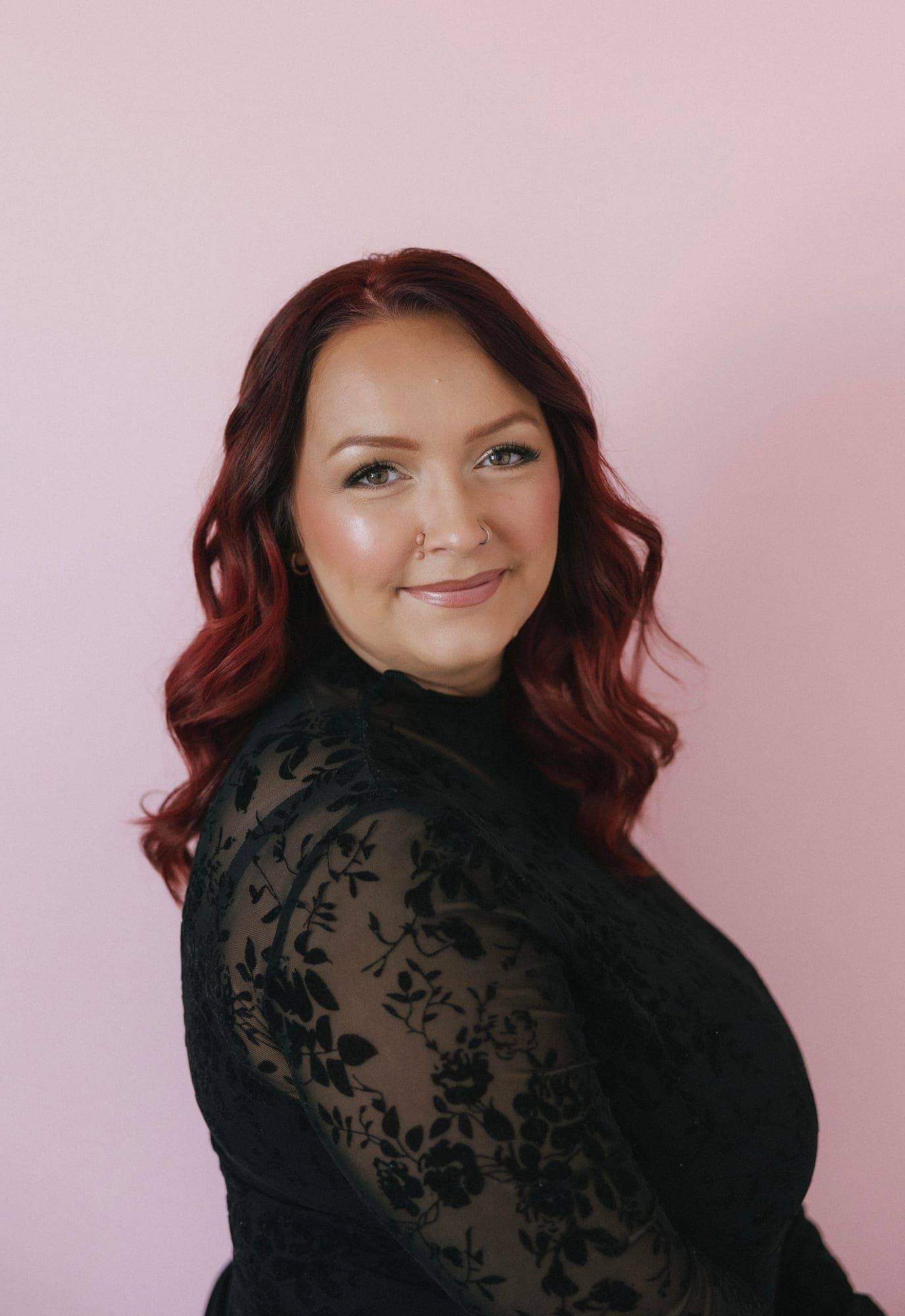Shealyn smiling against a soft pink wall